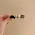 Gros plan détaillé de la barrette vintage avec perle, strass et motif de papillon doré - Nœud Noir