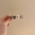 Gros plan détaillé d'une pince à cheveux vintage avec perles et strass brillants. - Carré Champagne