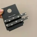 Primo piano di due fermagli per capelli grigi con strass a stella su cartoncino nero - Paia / Grigio
