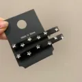 Primo piano di fermagli per capelli neri con strass a stella su cartoncino - Paia / Nero