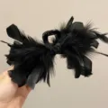 Detail view of large black ostrich feather shark clip for hair styling - L / Black