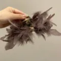 Close-up detail of the soft brown ostrich feathers on a large elegant hair claw clip - L / Mocha