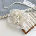 Chouchou élégant en dentelle crème avec nœud sur un plateau à bijoux - Chouchou Nœud en Dentelle Blanc Cassé