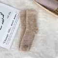 Detailed view of soft coral fleece sleep socks in light brown on a plush white rug - Sizes 39-44 / Khaki