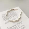 Elegant cream mesh braided headband in a French style shown on an open book prop - Flat Twist Braid / Creamy White Spiral