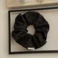 Oversized black scrunchie with bow patterns on a minimalist display tray - Bowknot Style / Black