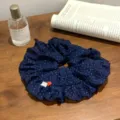 Détail d'un chouchou bleu marine à pois avec volants et un bouton en forme de cœur. - Style bouton coeur à pois bleu marine / Bleu marine