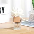 Close-up of a car vent diffuser with a white wooden flower and clear glass bottle. - Square Bottle (8ml) / Clear