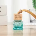 Detailaufnahme der blauen geometrischen Glas-Autoparfümflasche mit Holzdeckel und Kordel. - Hellblau