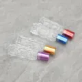 Dettaglio flacone roll-on in vetro per oli essenziali, superficie testurizzata e tappi. - Tappi colorati e sfere in vetro