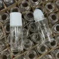 Vue de détail d'un flacon roll-on en verre transparent avec récipient vide et bille. - 30ml / Blanc