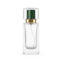Close-up detail of square clear glass perfume bottle with crystal cap and golden spray pump. - Green