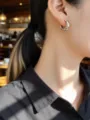 Primer plano de un pendiente de aro plateado trenzado llevado en la oreja - Estilo Plateado (K924) / Plata 925 / Grande (Aprox. 12mm)