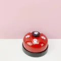Close-up detail shot of the red metal pet training buzzer bell with white paw print patterns. - Red Cat Paw