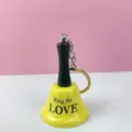 Primer plano detallado de un llavero de campana de llamada amarilla con mango negro. - Llaveros de cascabel amarillo love
