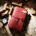 Vintage rotes Leder Reisetagebuch mit Messing-Clip und Flugzeug-Anhänger für Notizen. - Burgunderrot