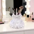 Close-up van een witte japonvormige make-up penseelhouder met fijne volant op het kaptafeltje. - Prinsessenjurk Stijl / Wit
