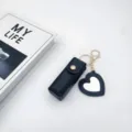 Close-up detail of the black leather lipstick case keychain with a cute heart mirror pendant. - Black Heart Mirrors