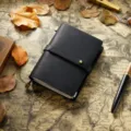 Carnet de voyage en cuir noir style rétro journal intime artisanal avec lanière et fermoir métallique. - Format passeport / Noir