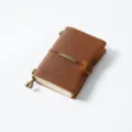 Vintage brown leather traveler notebook with metal engraved tag and elastic band closure. - Passport Size / Crazy Horse Brown