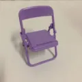 Close-up detail view of a purple mini folding chair phone stand and desktop decor. - Elegant Purple