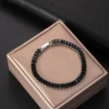 Elegant silver-toned bracelet with rectangular black zircons on a gold gift box. - Black