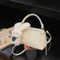 Cream-colored bucket bag with cute plush bunny charm and adjustable shoulder strap - With Charm / Off White
