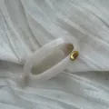 Detailansicht einer cremeweißen Marmor-Haarklammer mit goldenem Hand Made Metallschild - Hohl oval / Gelee-Weiß