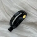 Detailansicht der schwarzen ovalen Haarspange mit goldenem Hand Made Etikett - Hohl oval / Hellschwarz