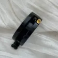 Nahaufnahme einer eleganten glänzend schwarzen ovalen Haarklammer mit Goldetikett - Hohles Quadrat / Hellschwarz