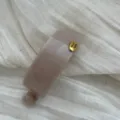 Detailansicht einer großen minimalistischen beigen Bananen-Haarklammer mit Gold-Emblem. - Quadratisch / Gelee Aprikose