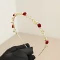 Detailed close-up of elegant gold headband with red velvet roses and white pearls - Rose Flower