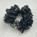 Nahaufnahme eines floralen Organza-Haargummis mit funkelnden Kristallperlen-Akzenten - Schwarz und Grau