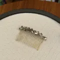Detailansicht eines eleganten goldenen Haarkamms mit facettierten grauen Kristallen. - Grau