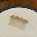 Nahaufnahme eines eleganten Haarkamms aus champagnerfarbenem Kristall mit goldenen Zinken. - Champagner