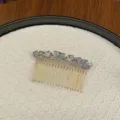Elegant gold-tone hair comb with faceted light blue crystals on a white textured tray. - Light Blue Grey