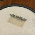 Detailed macro view of iridescent crystal stones on a gold-toned metal hair insert comb - Transparent Green