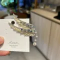 Macro view of luxurious angel wing hair clip with blue crystals and a pearl tassel - Gold