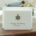Tarjeta de cumpleaños vintage blanca con dije de timón de bronce y sobre blanco incluido - Estilo Timón (305#)