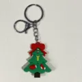 Detaillierte Nahaufnahme des grünen Weihnachtsbaum-Schlüsselanhängers mit einer roten Schleife - Schleife Handschuh Geschenk Baum Stil / Grün