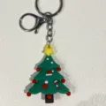 Nahaufnahme eines festlichen grünen Silikon-Weihnachtsbaum-Schlüsselanhängers mit Details. - Stern Socke Hut Weihnachtsbaum Stil / Grün