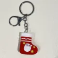 Nahaufnahme eines festlichen roten Silikon-Weihnachtssocken-Schlüsselanhängers mit Weihnachtsmann - Weihnachtsmann Kopf Weihnachtsstrumpf Stil / Rot