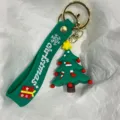 Detailansicht eines grünen Silikon-Weihnachtsbaum-Schlüsselanhängers mit Gurt - Weihnachtsbaum mit Sternen, Stab und Socke