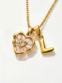 Close-up detail shot of a gold-toned necklace featuring a mother-of-pearl heart and letter L. - L