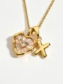 Gold tone necklace detail featuring a mother of pearl heart pendant and letter X charm close up. - Letter X