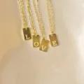 Nahaufnahme Detail von goldenen Edelstahl rechteckigen Anhänger Halsketten Liebeswort. - Buchstabe A