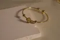 Closeup view of a gold-plated open cuff bracelet featuring a chic clover motif and polished beads. - Original Color