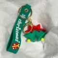 Nahaufnahme eines festlichen grünen Weihnachtsglocken-Schlüsselanhängers mit roter Schleife. - Grüne Glocken mit roter Schleife