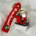 Nahaufnahme eines Weihnachtsmann-Schlüsselanhängers mit rotem 'Christmas' Silikonband - Weihnachtsmann Im Schlitten