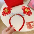 Diadema festiva roja de Año Nuevo Chino con nudos dorados y detalles de espumillón brillante. - Diadema Nudo Chino de Fortuna / Talla única